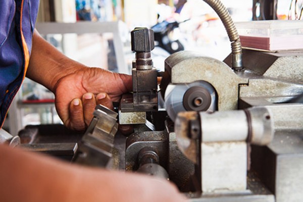 Locksmith in Workshop Makes New Key. Professional Making Key in