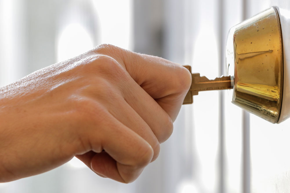 hand sticking key into lock to open it 